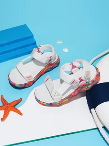 Gros plan de sandales de plage blanches pour filles avec semelles colorées sur fond marin