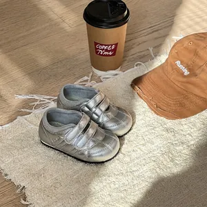 Primo piano di scarpe da bambino argento metallizzato con velcro su un tappeto ruvido