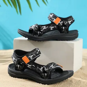 Detail view of camouflage kids beach sandals with orange straps on a beach background