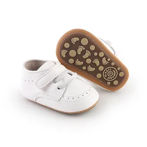 White baby prewalker shoes with velcro straps and a non-slip patterned sole.