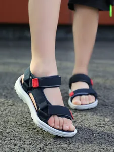 Close-up detail of children's navy blue non-slip sandals worn on an outdoor ground.