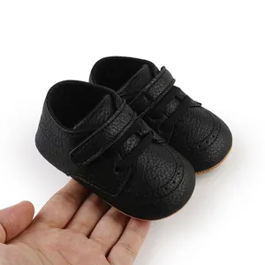 Detailed view of soft black leather baby walker shoes held in hand for size reference