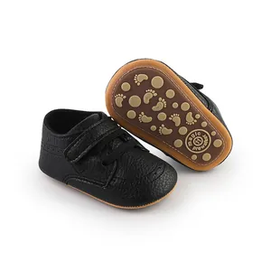 Detail showing black faux leather baby pre-walker shoe with non-slip sole pattern.