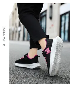 Primo piano di scarpe sportive nere e rosa da bambina su una strada