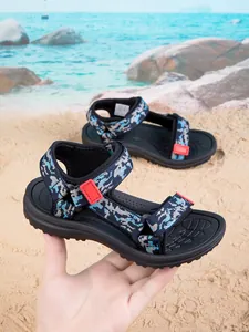 Detailed view of kids camouflage sports sandals with red buckles on a sandy beach