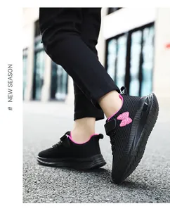 Dettaglio di eleganti sneakers in mesh nero per bambine con toppa a farfalla rosa decorativa.