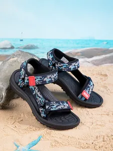 Children's non-slip camouflage sandals displayed on a sunny beach background detail view.