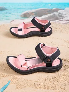 Detailed view of pink and black non-slip children's beach sandals on a sunny sandy shore