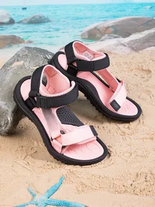 Detail view of pink non-slip children's beach sandals on a sandy background