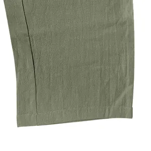 Close-up of olive green linen fabric texture and hem stitching on casual pants.