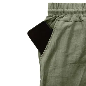 Close-up of side pocket on men's olive green linen casual pants with a phone inserted
