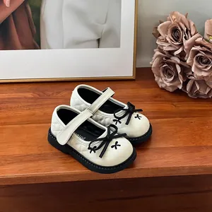 Détail de chaussures Mary Jane blanches pour fillettes avec nœuds noirs et matelassage