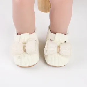Close-up detail of cream baby walking shoes featuring a decorative mesh bow design.