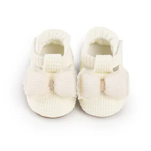 Close-up of cream baby walking shoes with waffle texture and oversized tulle bows.