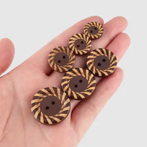 Six assorted sizes of natural poplar wood buttons with striped patterns held in hand
