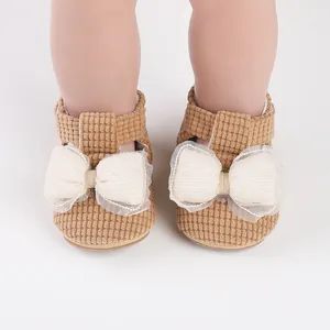 Close-up detail of brown corduroy baby walking shoes with white mesh bow decoration