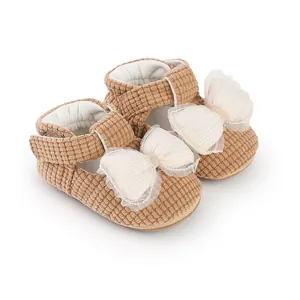Close-up of brown corduroy baby pre-walker shoes with elegant white mesh bows