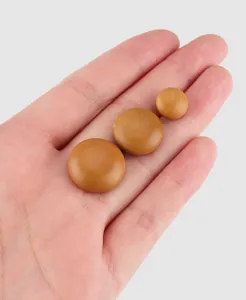 Close-up of three sizes of natural poplar wood buttons on a palm for scale.
