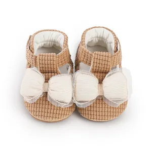 Detailed view of brown corduroy baby walking shoes featuring large white decorative bows