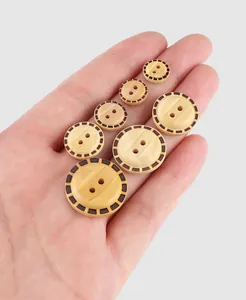 Close-up of decorative poplar wood buttons in various sizes held in a hand palm