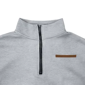Macro view of gray half-zip men's sweatshirt featuring a stand collar and leather detail.