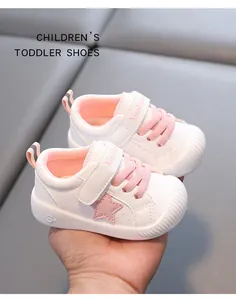 Detalle de zapatos blancos para niños con estrella rosa y suela blanda de cuero impermeable