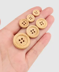 Various sizes of natural bamboo buttons with 4-hole design held in hand for scale