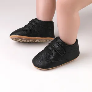Close-up of classic black faux leather baby walking shoes with hook and loop strap