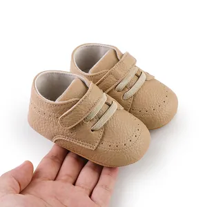 Soft sole brown faux leather baby walking shoes shown for size scale on adult hand