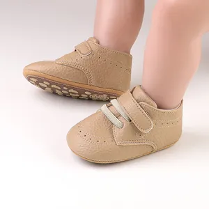 Detailed close-up shot of tan faux leather baby walking shoes with brogue perforations