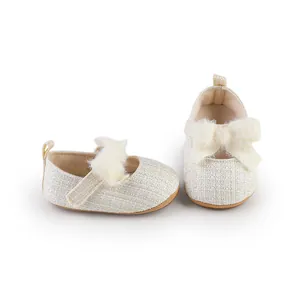 Detailaufnahme von cremefarbenen Tweed-Babyschuhen mit einer weichen Plüschschleife
