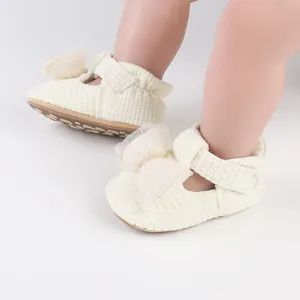 Detail view of cream corduroy baby walking shoes with a large mesh bow detail.