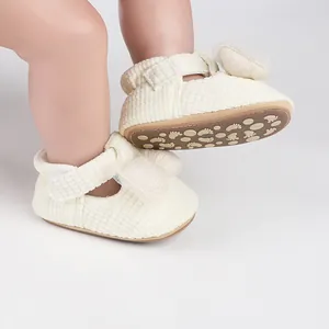 Macro view of cream baby walking shoes featuring soft bow and anti-slip footprint sole