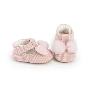 Detailed macro view of pink corduroy baby shoes with a soft tulle bow decoration.