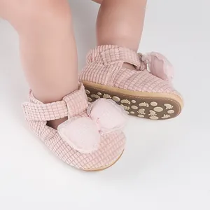 Close-up of pink corduroy baby walking shoes with large decorative bow detail
