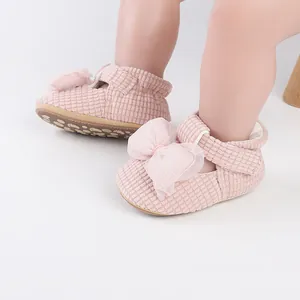Close-up of pink baby walking shoes with a large mesh bow and soft corduroy texture