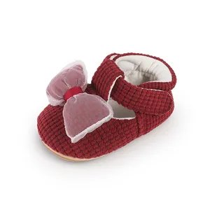 Close-up of red textured fabric baby walking shoes with a large mesh bow detail