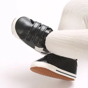 Dettaglio di scarpe nere da neonato con motivo a stella bianca e chiusura velcro.