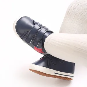Dettaglio di scarpe primi passi per neonati blu navy con stella rossa e suola morbida.