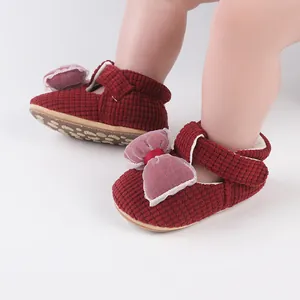 Detail view of red baby walking shoes with waffle texture and mesh bow on infant feet.
