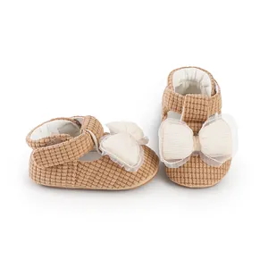 Detailed close-up of brown corduroy baby walking shoes with white mesh bow decoration.