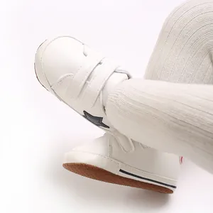 Dettaglio di scarpine primi passi bianche in pelle con velcro e decoro a stella