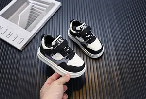 Close-up of black and white toddler sneakers featuring a quilted design and velcro straps