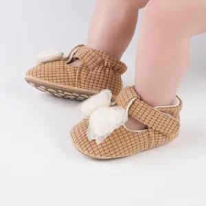Detailed view of brown corduroy baby walking shoes featuring a white bow and velcro strap