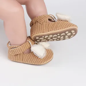 Detail view of brown corduroy baby walking shoes featuring a large white bow decoration