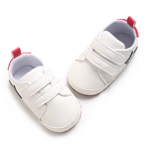 Vista dall'alto di scarpe primi passi bianche per neonati con linguetta rossa