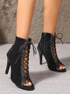 Detalle del diseño de cordones en botines de gamuza negra con tacón de aguja y punta