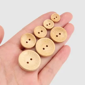 Premium set of natural round bamboo buttons in various sizes held in hand for scale