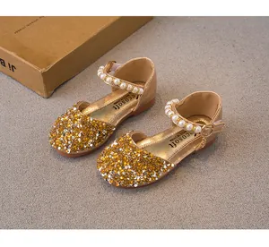 Detail shot of golden girls' princess shoes with sequins and pearl-beaded straps