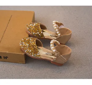 Detail of gold sequined girls' princess shoes with elegant pearl straps and buckles